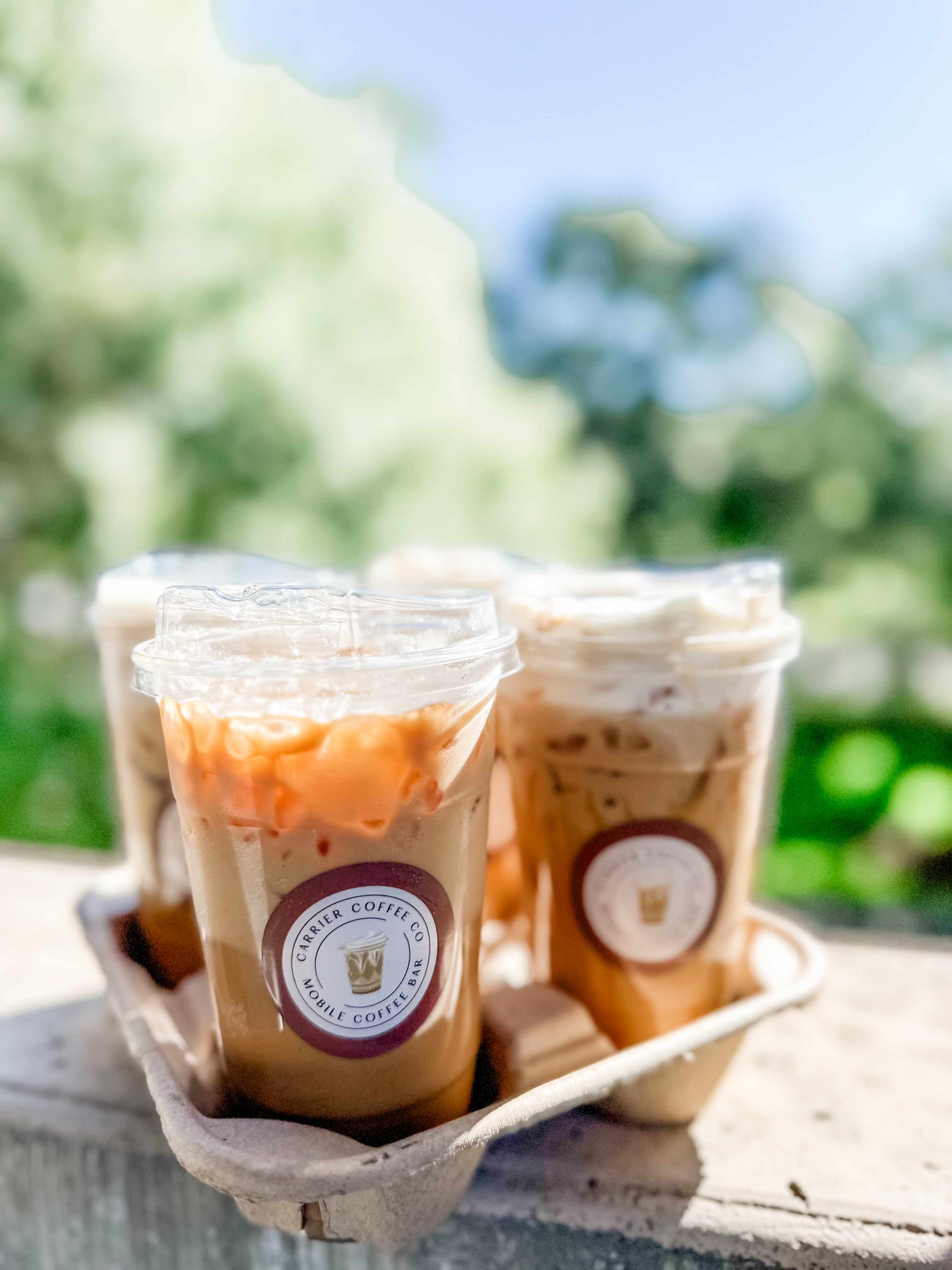 A carrier tray of iced lattes in the sun