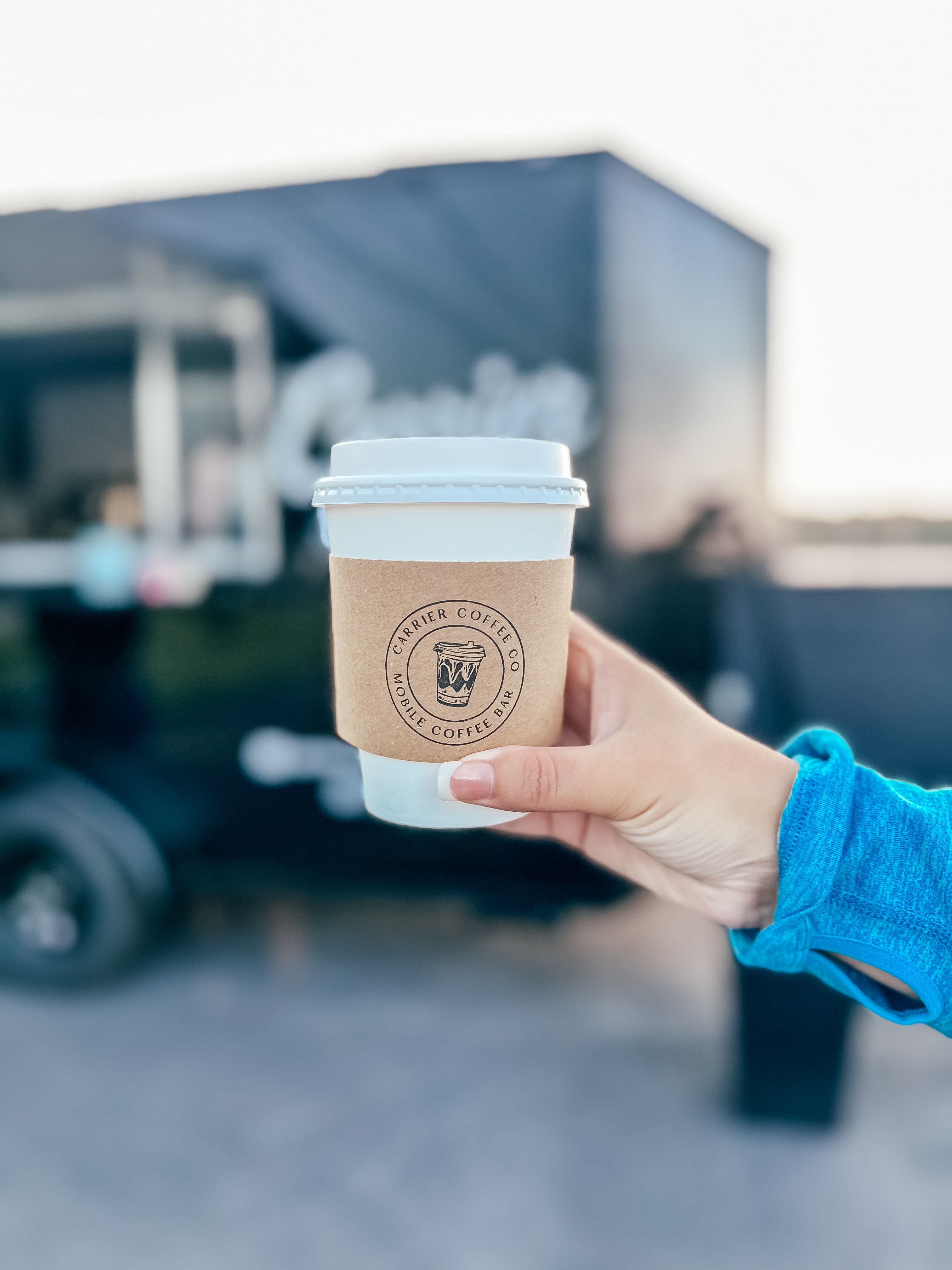 A hot latte held up in front of the trailer